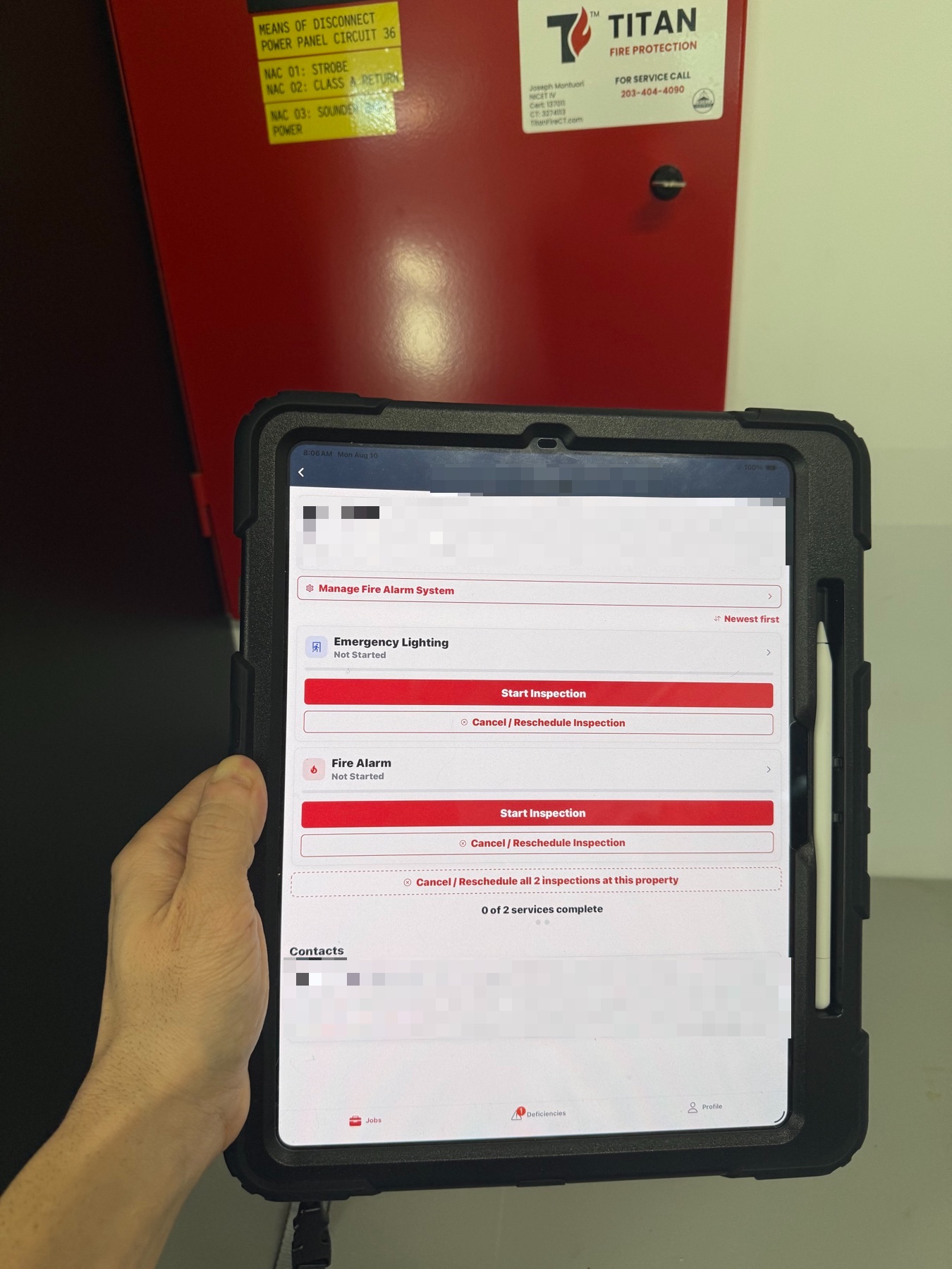 An iPad running CodeGreen ITM held in front of an open fire alarm control panel